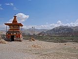 Mustang 01 01-1 Tsarang Entrance Chorten The trail descends from Lo Manthang (3910m) to cross a stream before ascending to the Lo La (3950m) with our last view of the walled city of Lo Manthang. The trail then traverses the Tholung Valley before reaching a ridge (3580m) looking over the village of Tsarang (3560m). The trail descends to cross the Tsarang Chu, and climbs 125m to Tsarang, the second largest village in Mustang. I walked across the village to see the entrance chorten nicely framing the village and the Tsarang gompa and old dzong.